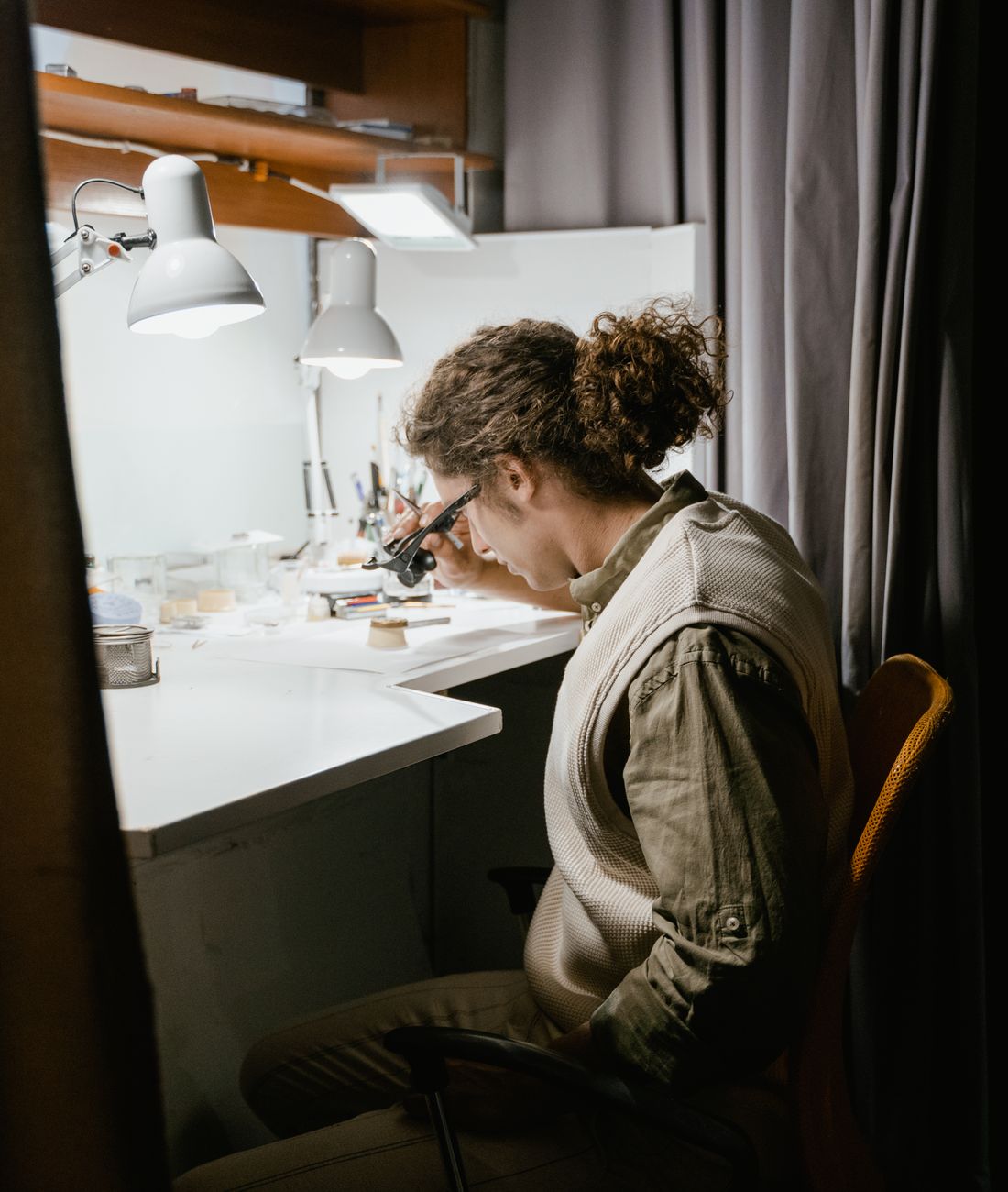 Jeweller hand-finishing a piece under a loupe in the workshop